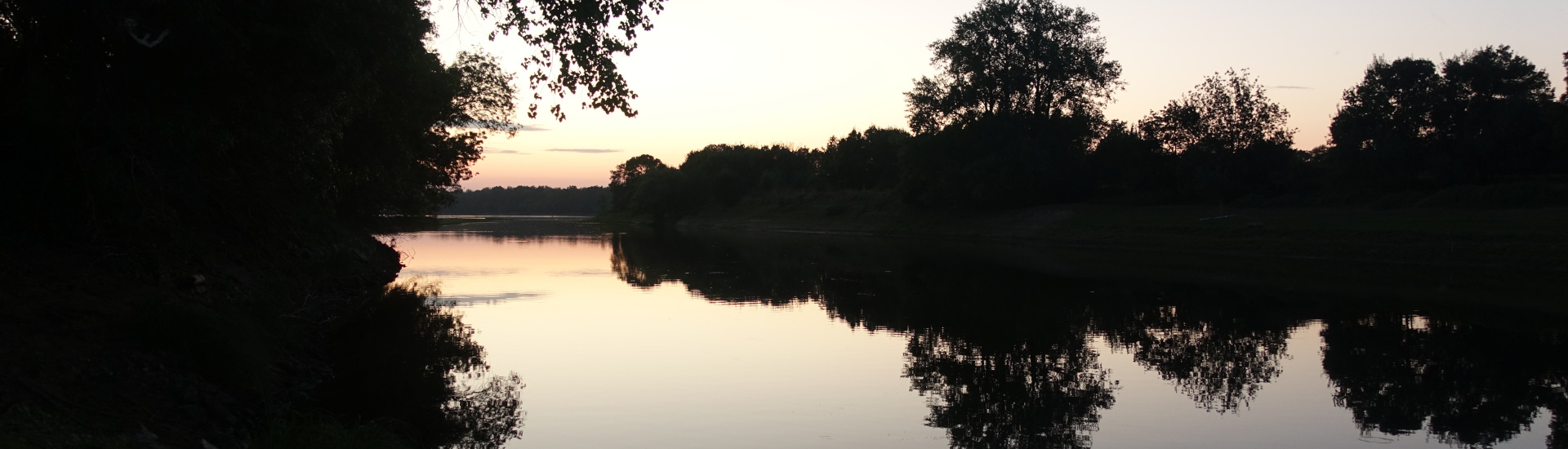 Abendstimmung an der Loire. Die Silhouetten der Bäume am anderen Ufer spiegeln sich an der Wasseroberfläche.