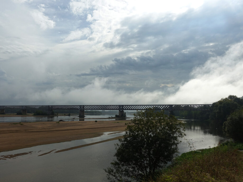 Eisenbahnbrücke über die Loire vor einem Himmel mit Nebelschwaden und Gewitterwolken