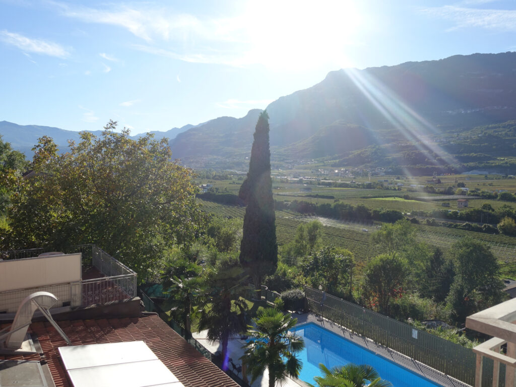 Blick vom Hotelbalkon auf den blauen Pool im Hotelgarten.